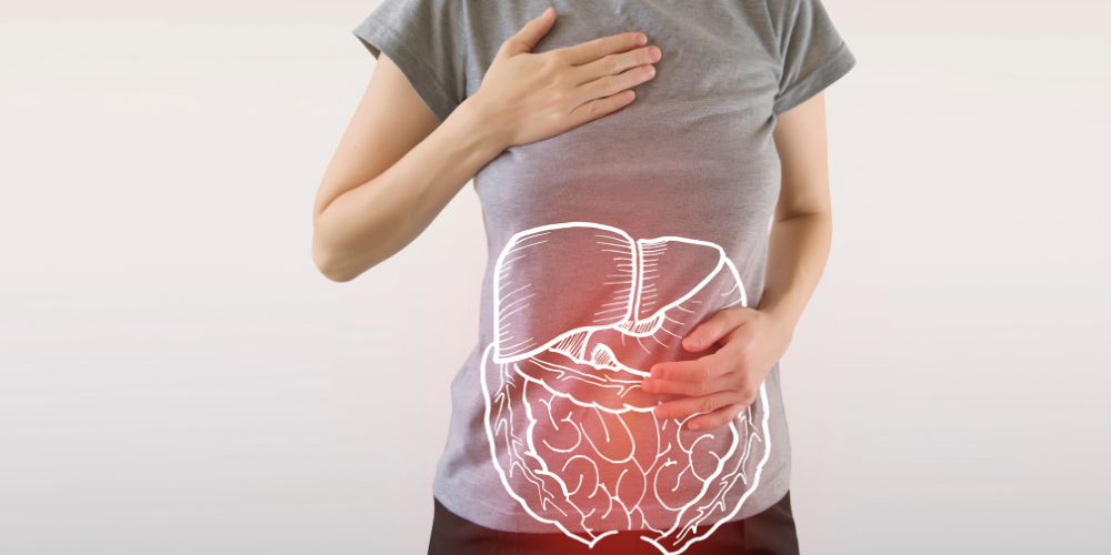 Person holding stomach with illustrated digestive system overlay.