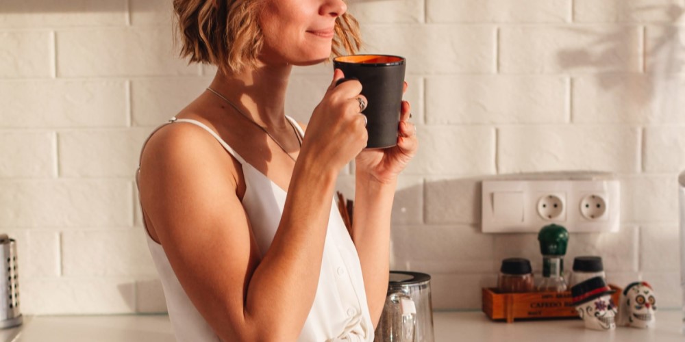 Woman drinking from a mug in a bright kitchen 