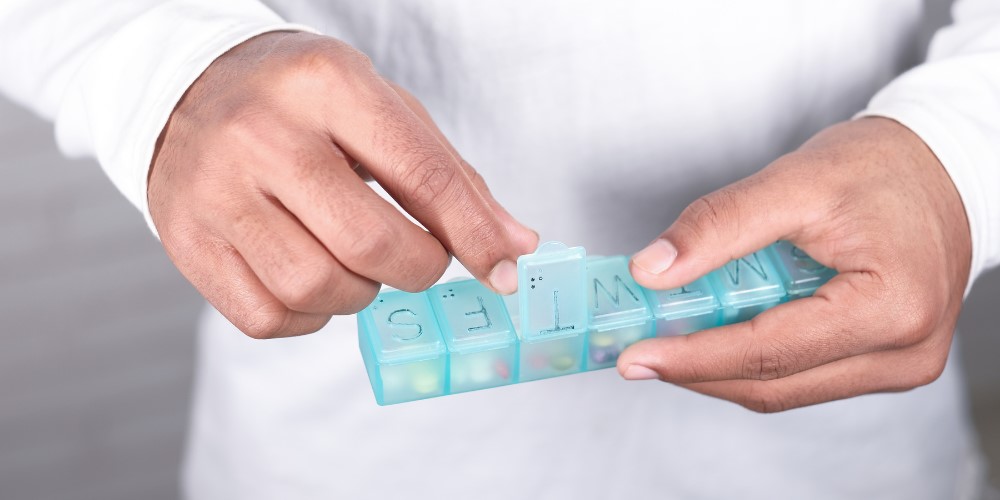Person holding a weekly pill organizer