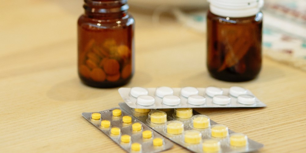 Supplement tablets in blister packs and brown glass bottles on table 