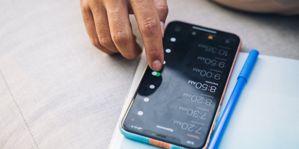 Hand adjusting alarm times on a smartphone 